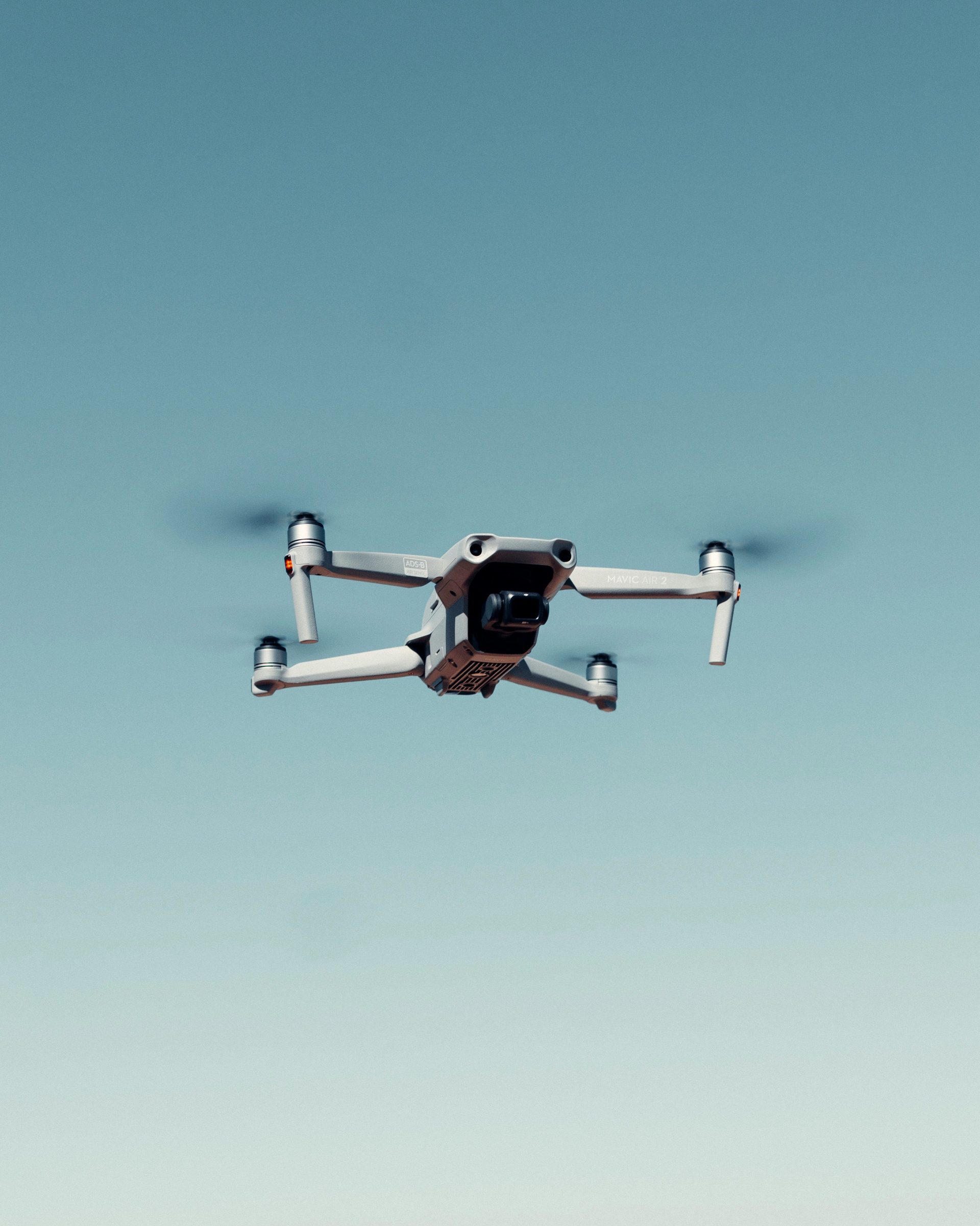 black and white drone flying under blue sky during daytime